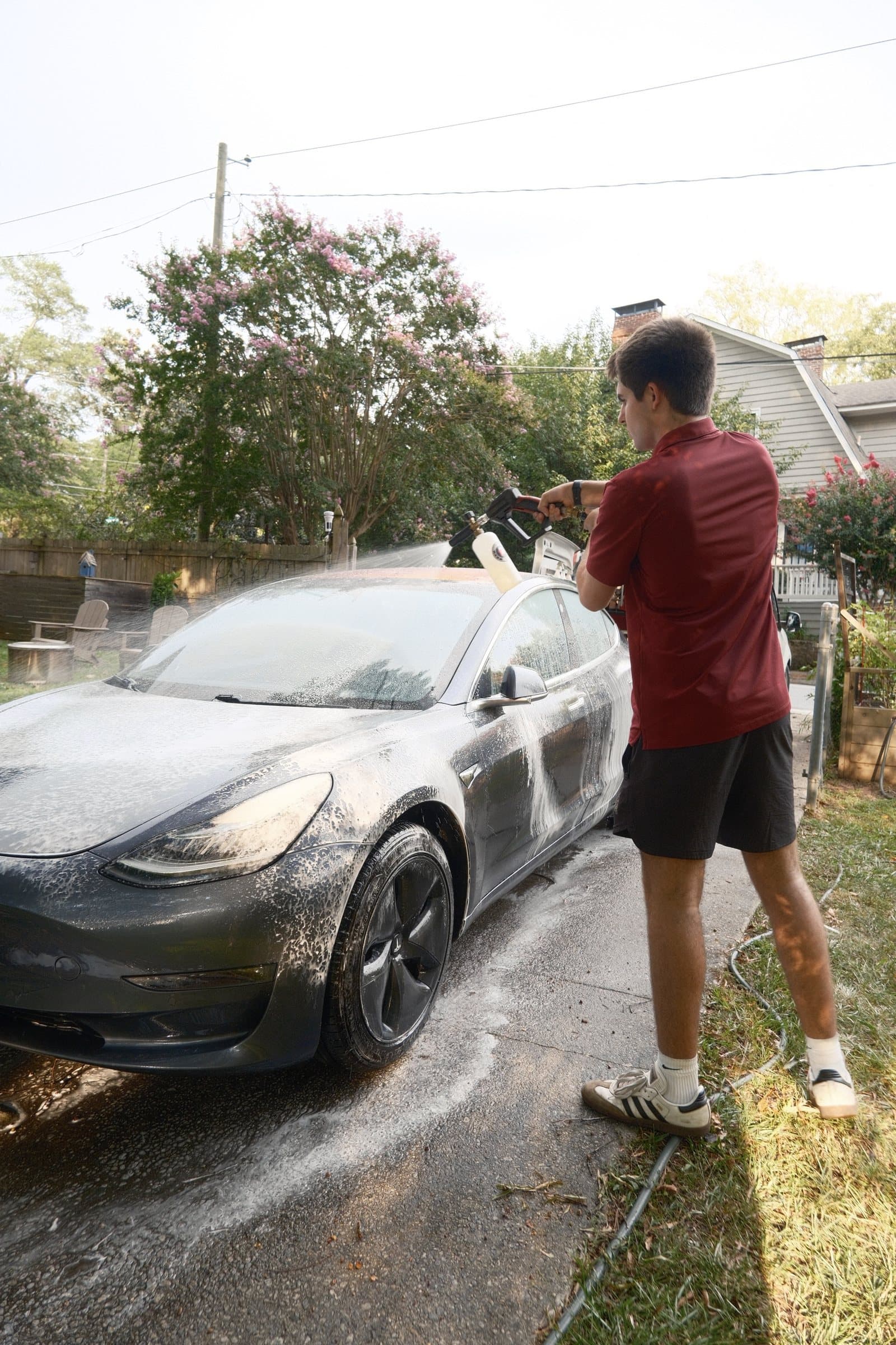 Every Detail technician foam washing a Tesla in a residential driveway
